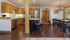 A spacious kitchen with wooden cabinets, a central island, and a dining area with a large table and chairs.