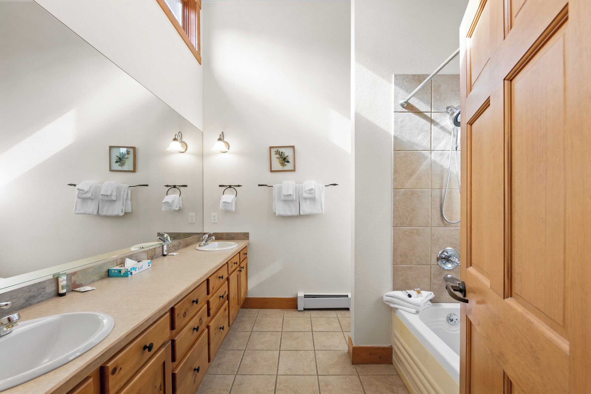 A modern bathroom with two sinks, a large mirror, and a shower area.