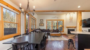 A spacious dining area with a long table and chairs, a sofa, and a fireplace.