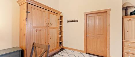 A room with a wooden wardrobe, a closed door, and a patterned rug.