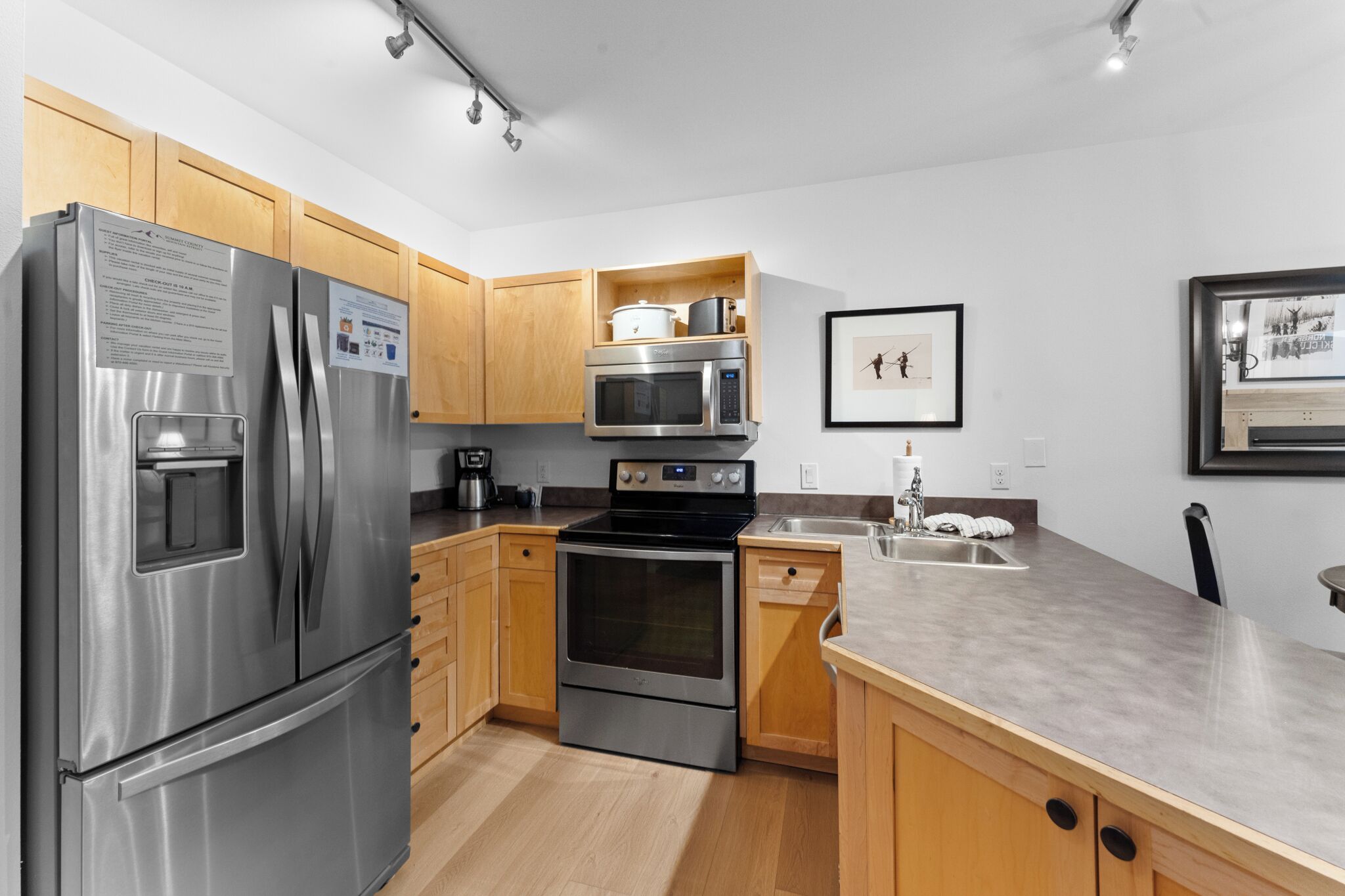 A modern kitchen with stainless steel appliances, wooden cabinets, and a granite countertop.
