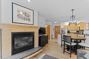 A modern kitchen with wooden cabinets, a built-in stove, and a dining area with a table and chairs. - Sm8153-1 (Keystone)