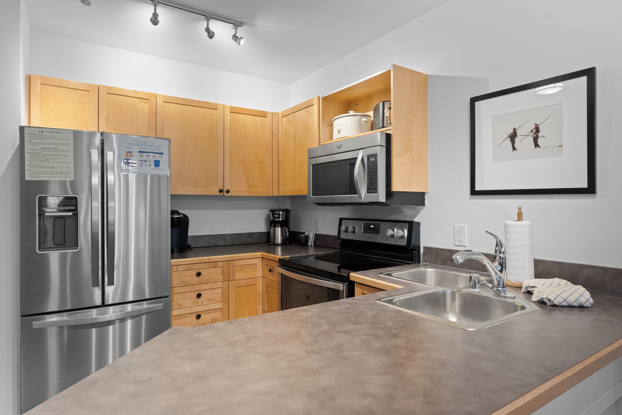 A modern kitchen with stainless steel appliances, wooden cabinets, and a granite countertop.
