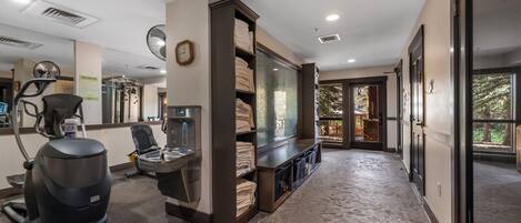 A gym with exercise equipment, a large mirror, and a wall-mounted fan.