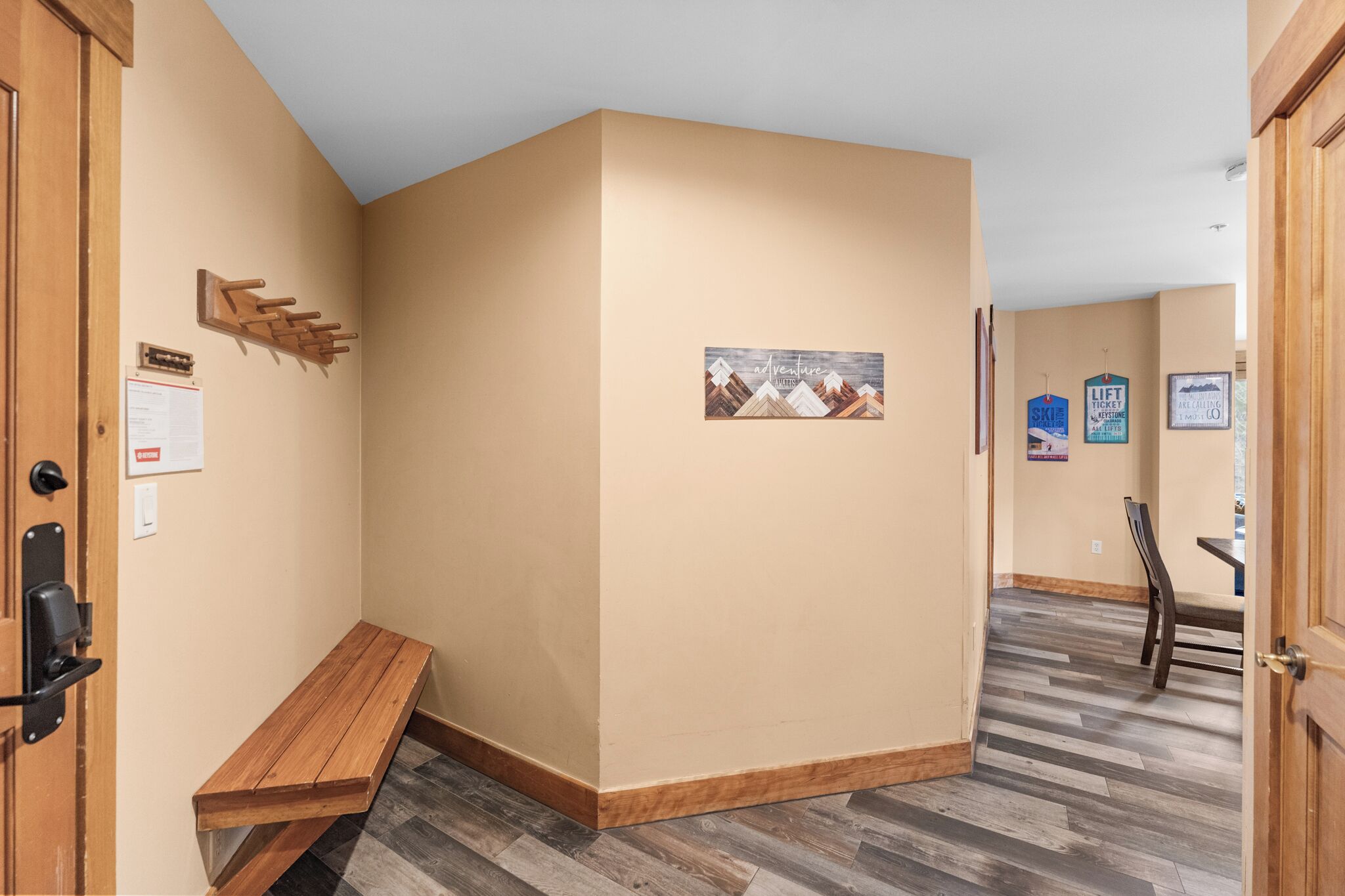 A hallway with a wooden bench, beige walls, and a wooden floor.