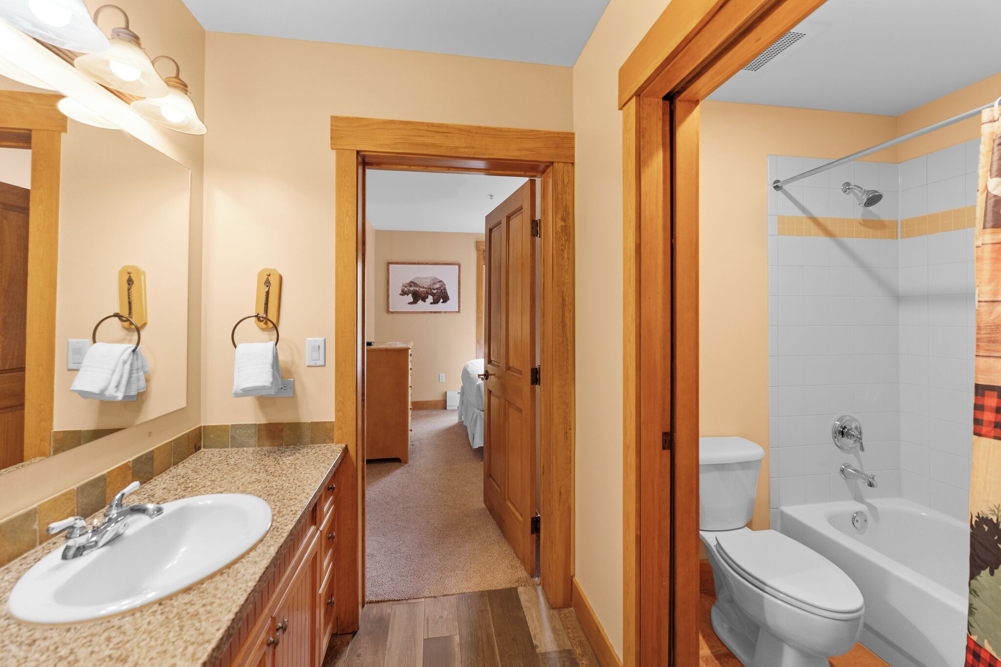 A bathroom with a sink, toilet, and bathtub. There is a wooden door leading to another room.