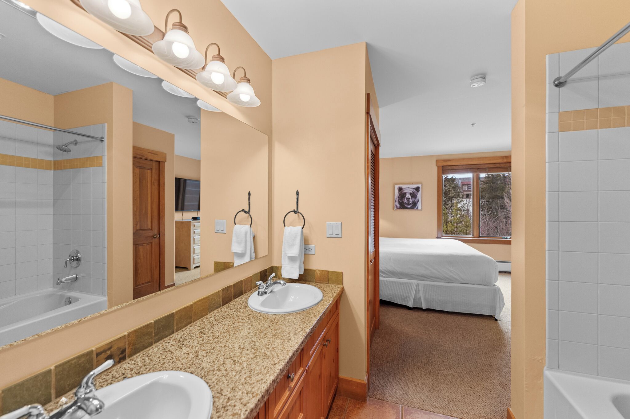 A bathroom with a double sink, a large mirror, and a shower.