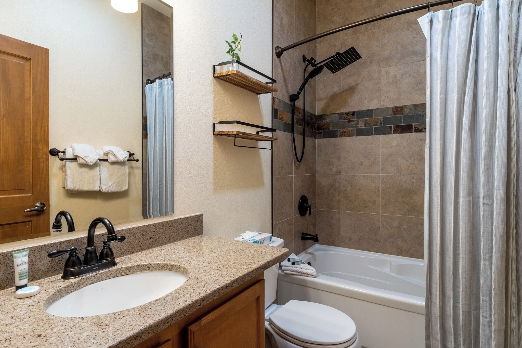 Une salle de bain équipée d’un lavabo, d’un miroir, d’un porte-serviettes, d’une douche et de toilettes.