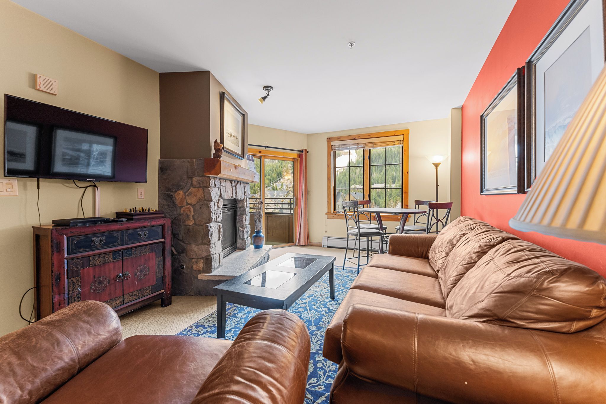 A living room with a stone fireplace, leather sofa, and a flat-screen TV.