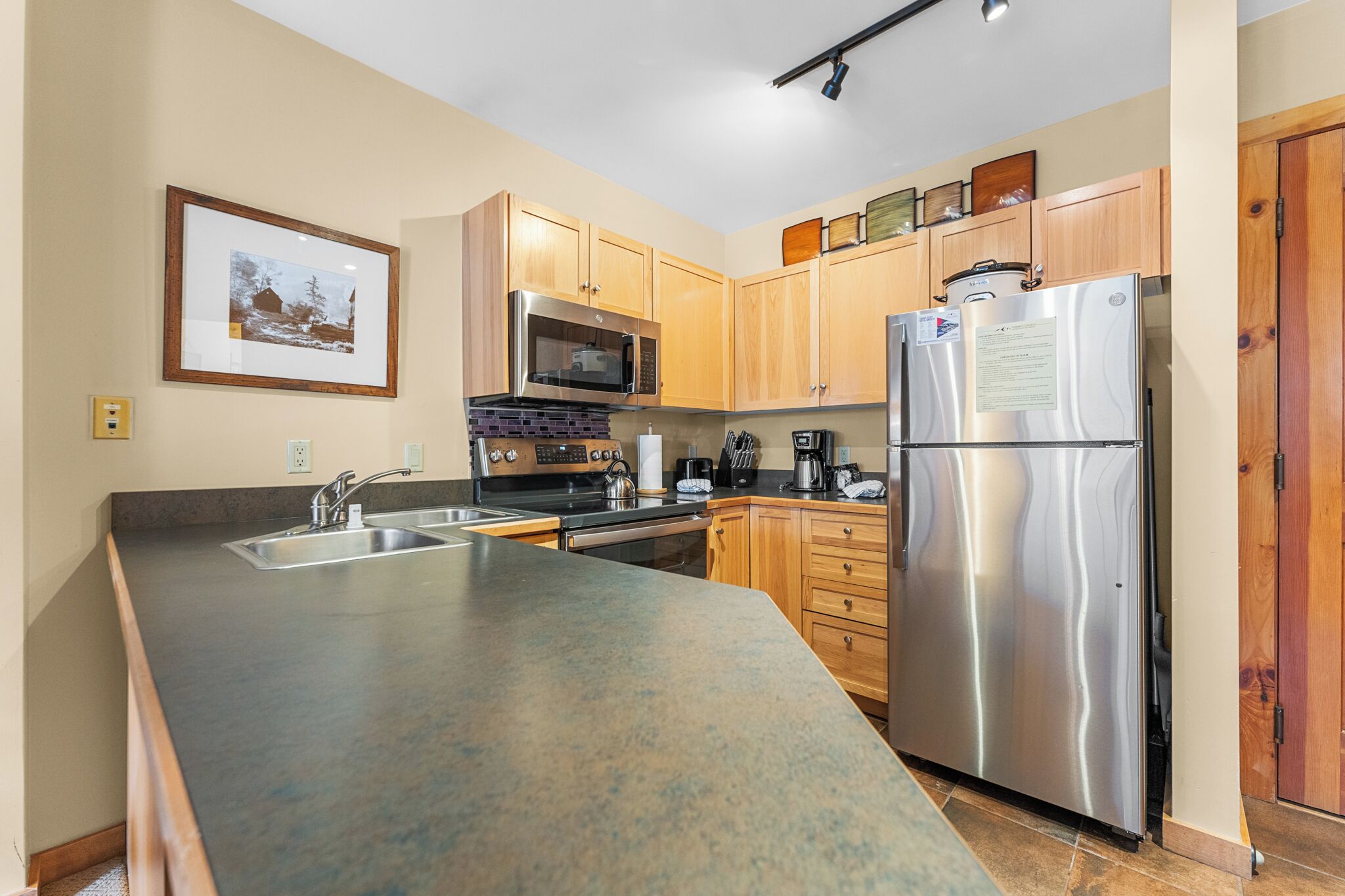 A modern kitchen with wooden cabinets, stainless steel appliances, and a granite countertop.