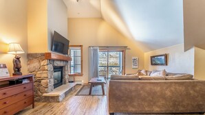 A cozy living room with a stone fireplace, a flat-screen TV, a sofa, and a wooden floor. - Dl8536-1 (Keystone)