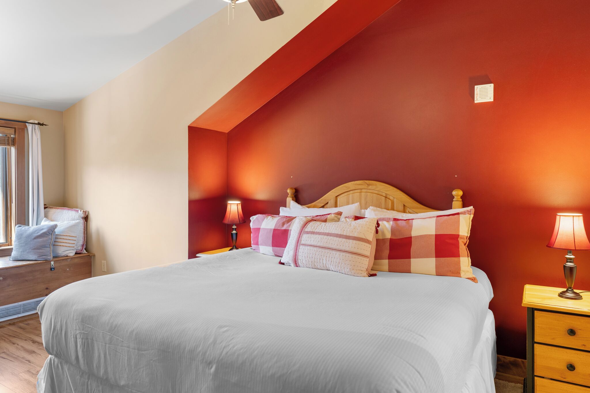 A neatly made bed with a checkered pillow and two bedside lamps.