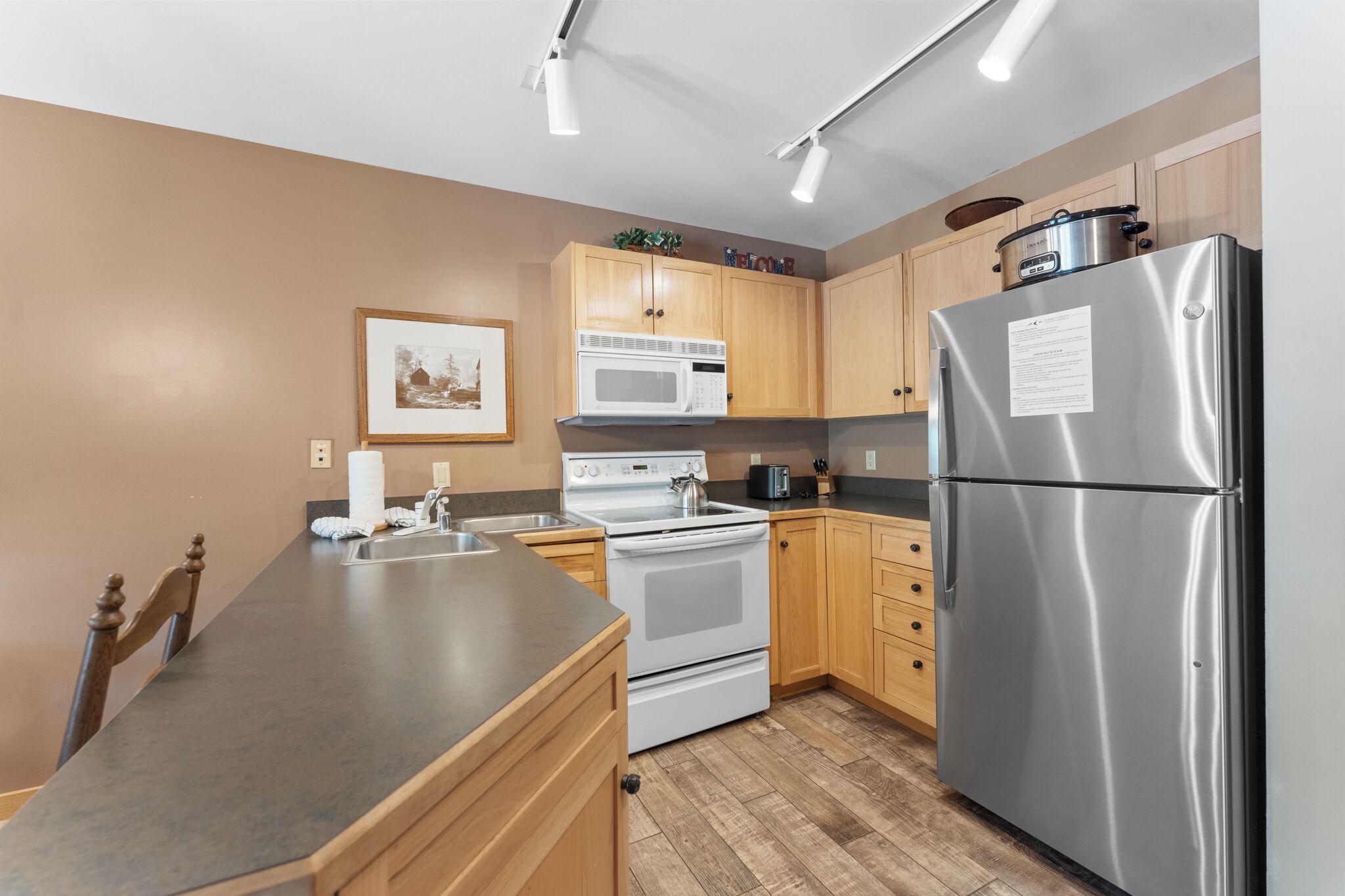 A modern kitchen with stainless steel appliances, wooden cabinets, and a granite countertop.