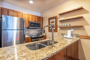A modern kitchen with granite countertops, stainless steel appliances, wooden cabinets, and built-in shelves. - Rh2271-2 (Keystone)