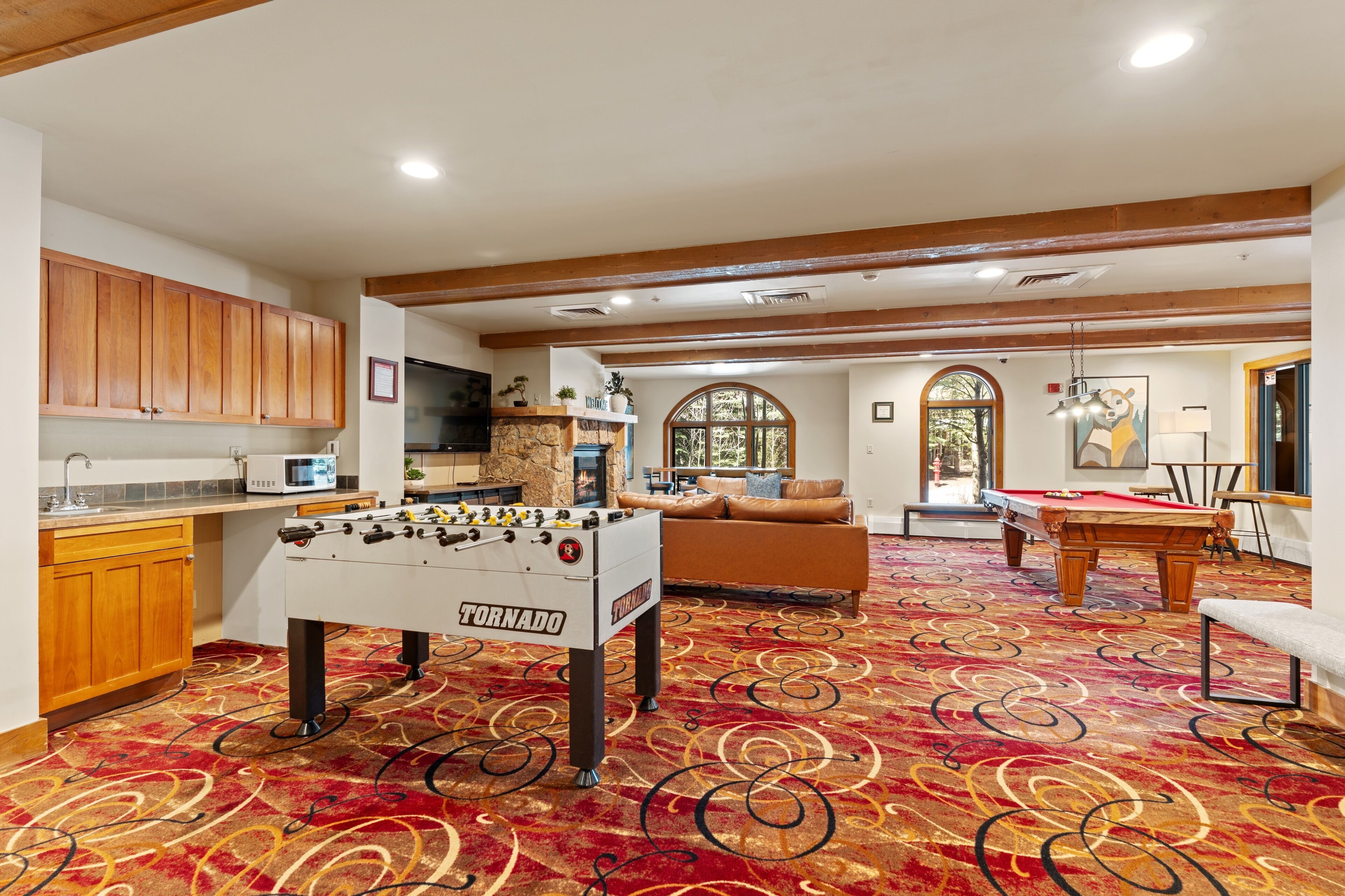 Une pièce spacieuse équipée d’un baby-foot, d’une table de billard et d’un coin salon confortable.