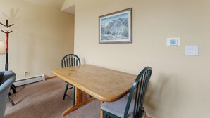 A dining area with a wooden table and four chairs, a coat rack, and a framed picture on the wall. - Snake River Village #29 (Keystone)