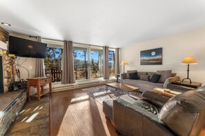 A modern living room with a large flat-screen TV, a sofa, a coffee table, and a fireplace. - Pines #2165 (Keystone)