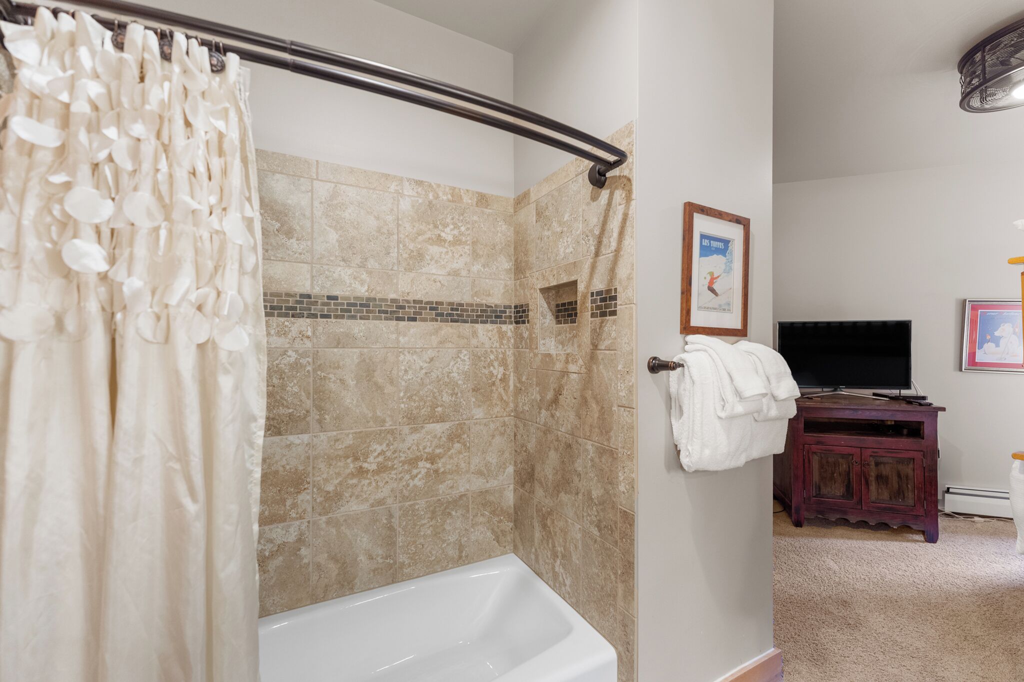 Un bagno con doccia, vasca, mobile lavabo con specchio e televisore.
