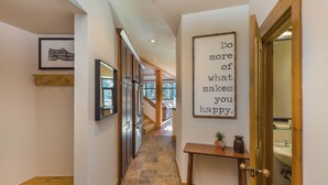 A hallway with a wooden bench, a stone-tiled floor, framed pictures, and a motivational quote on the wall. - Ski Tip #8723 : 2 (Keystone)