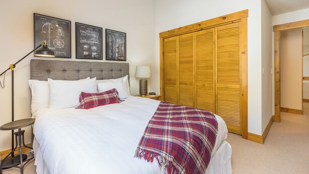 A neatly made bed with white linens and a plaid blanket, a bedside lamp, and two framed blueprints on the wall. - Ski Tip #8723 : 2 (Keystone)