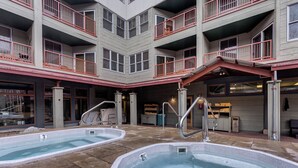 A multi-story building with a rooftop pool area, including two hot tubs and a covered seating area. - Silver Mill #8251 (Keystone)