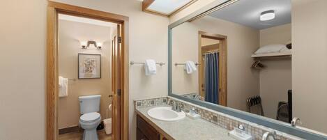 Un bagno con due lavandini, un water, uno specchio e una cabina doccia.