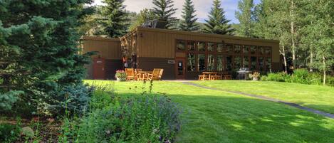 Un chalet doté d’une grande terrasse, entouré d’un jardin bien entretenu et d’arbres imposants.