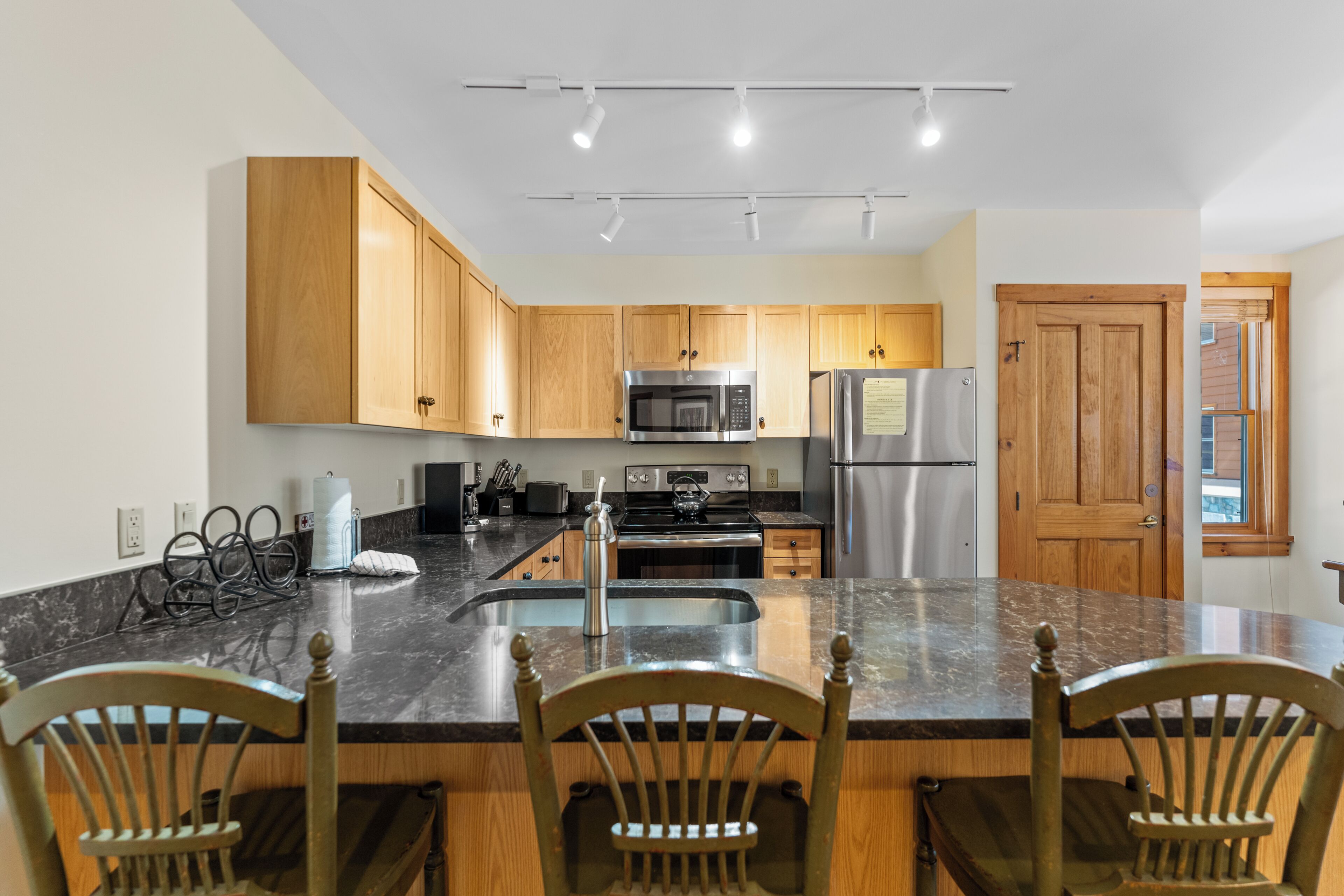 Une cuisine moderne avec des meubles en bois, des appareils en acier inoxydable et un plan de travail en granit.