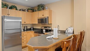 A modern kitchen with wooden cabinets, stainless steel appliances, and a central island with seating. - Dakota Lodge #8517 (Keystone)
