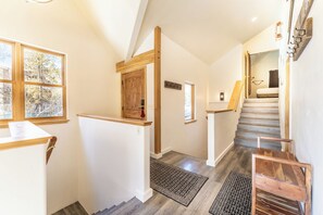 Eine Treppe mit Holzwangen und Blick ins Freie durch große Fenster.