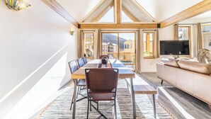 A spacious room with a high ceiling, a dining table with chairs, a sofa, and a TV.