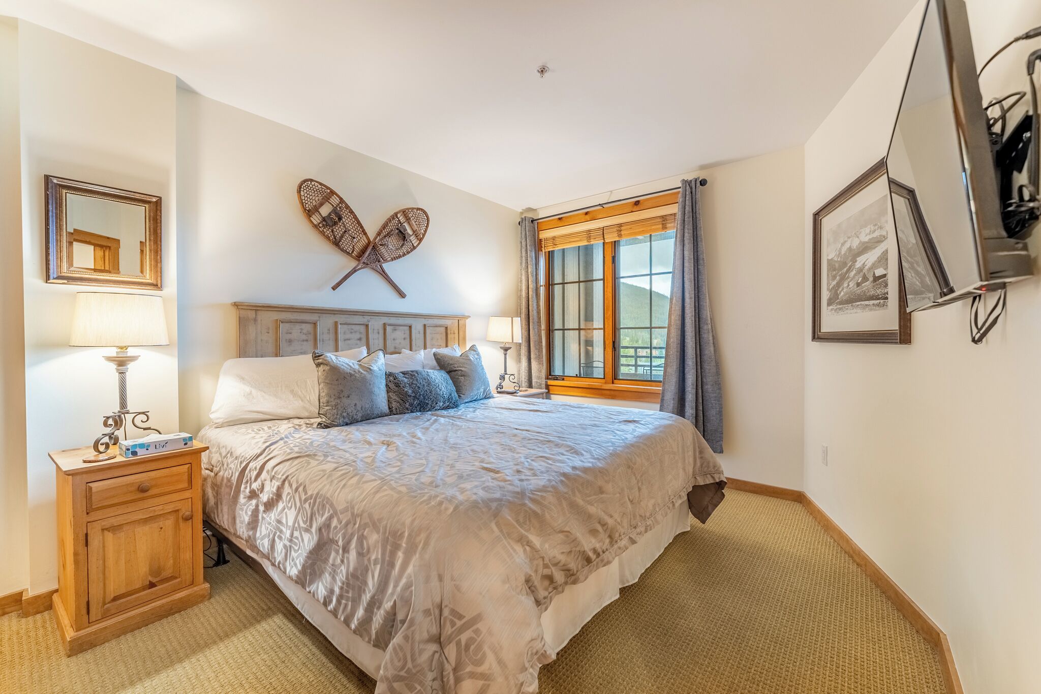 Ein ordentlich eingerichtetes Schlafzimmer mit einem großen Bett, Nachttischen, einem Fenster mit Vorhängen und Wanddekoration.