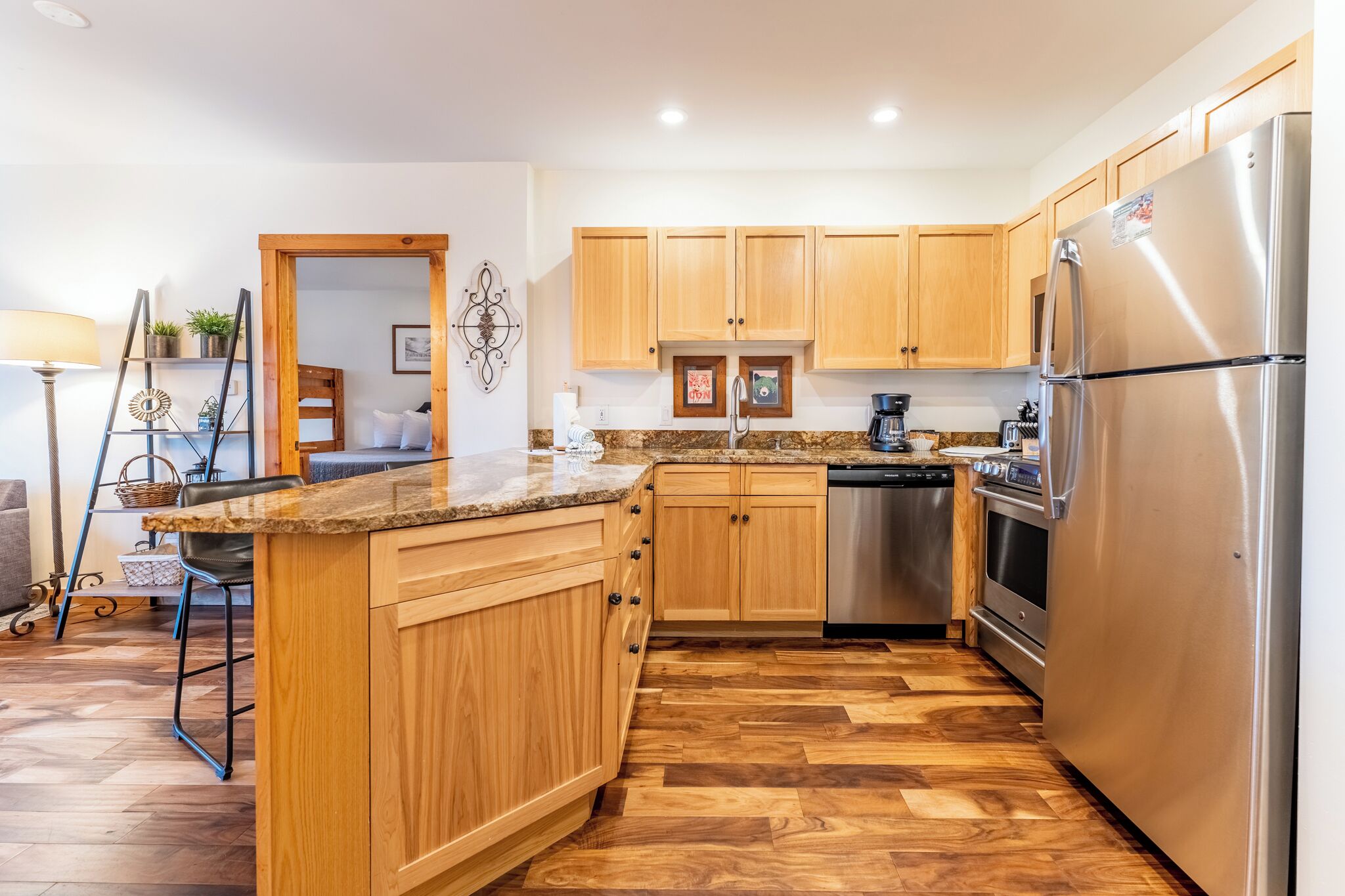 A modern kitchen with wooden cabinets, stainless steel appliances, and a herringbone wood floor.