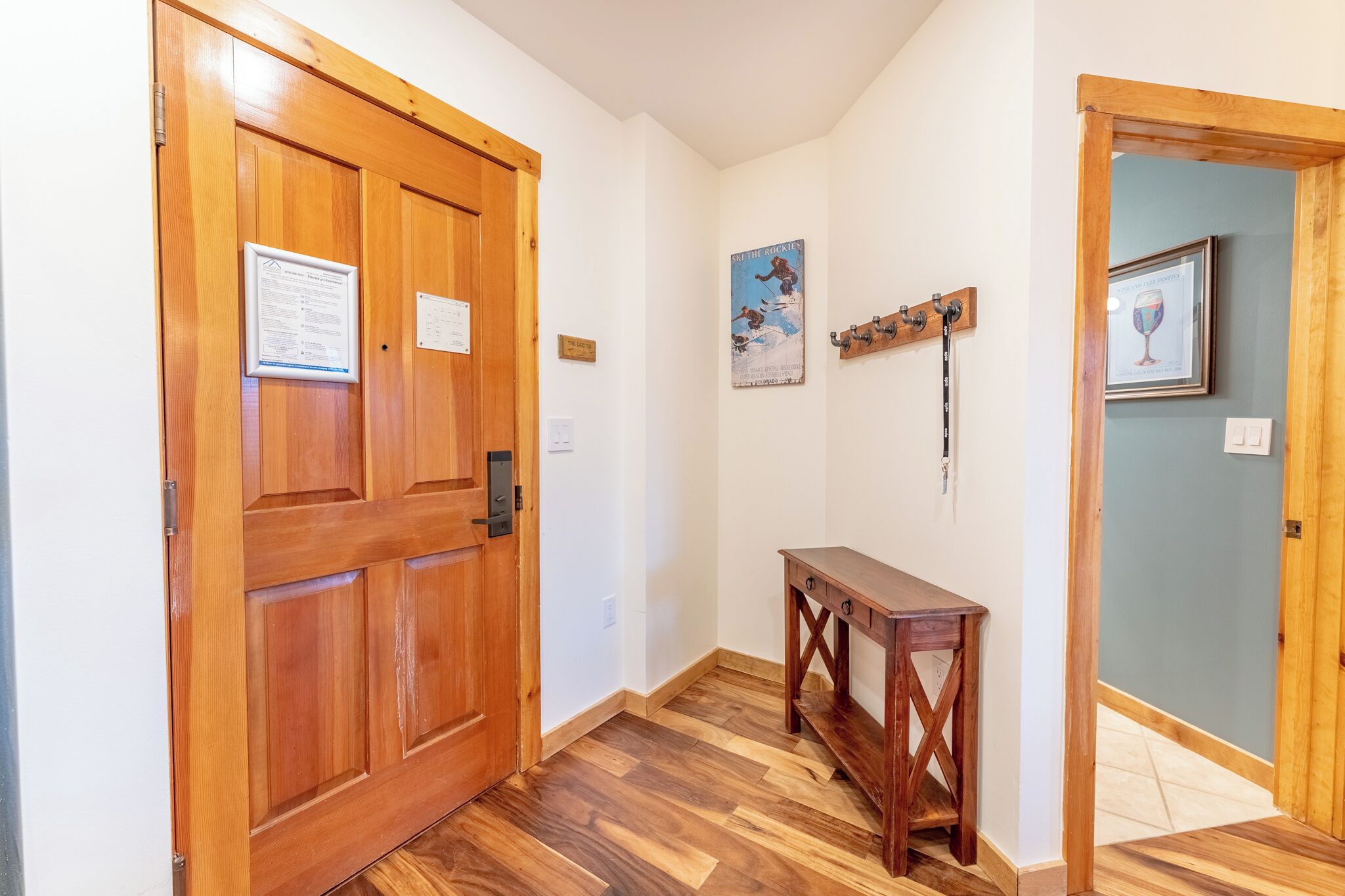 A hallway with wooden doors, a wooden bench, and a wall-mounted coat rack.