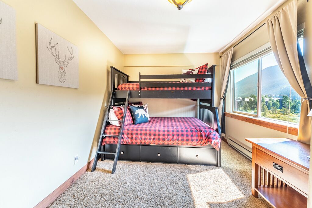 Une chambre avec des lits superposés, un bureau et une vue sur l’extérieur.