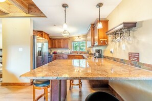 Una cocina amplia con encimeras de granito, gabinetes de madera y electrodomésticos de acero inoxidable.