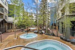 A spa area with hot tubs, stone flooring, and a wooden deck.