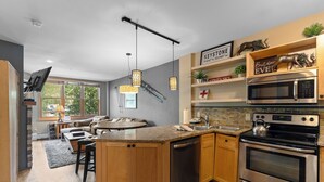 A modern kitchen with a central island, stainless steel appliances, and wooden cabinetry. - Sm8170-1 (Keystone)