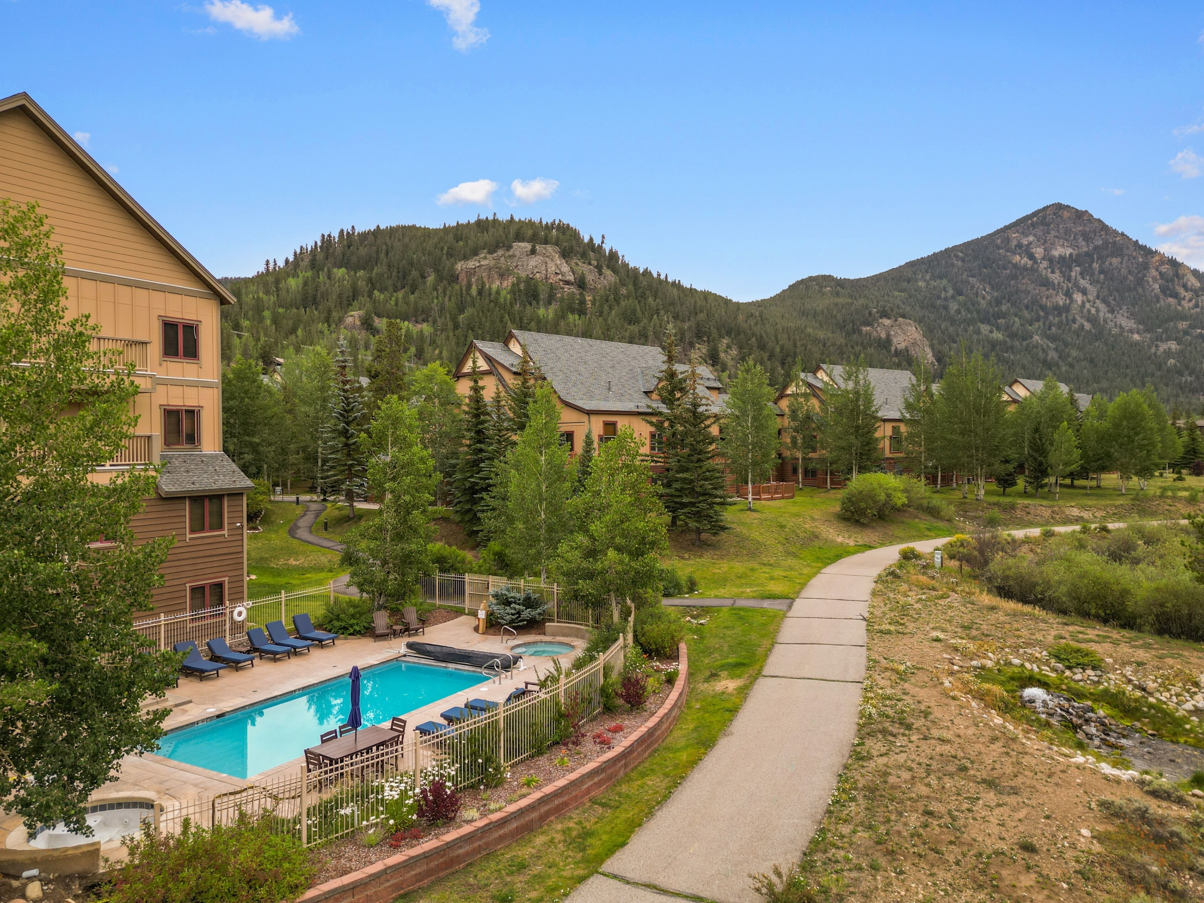A residential area with a swimming pool, lounge chairs, and a walking path.
