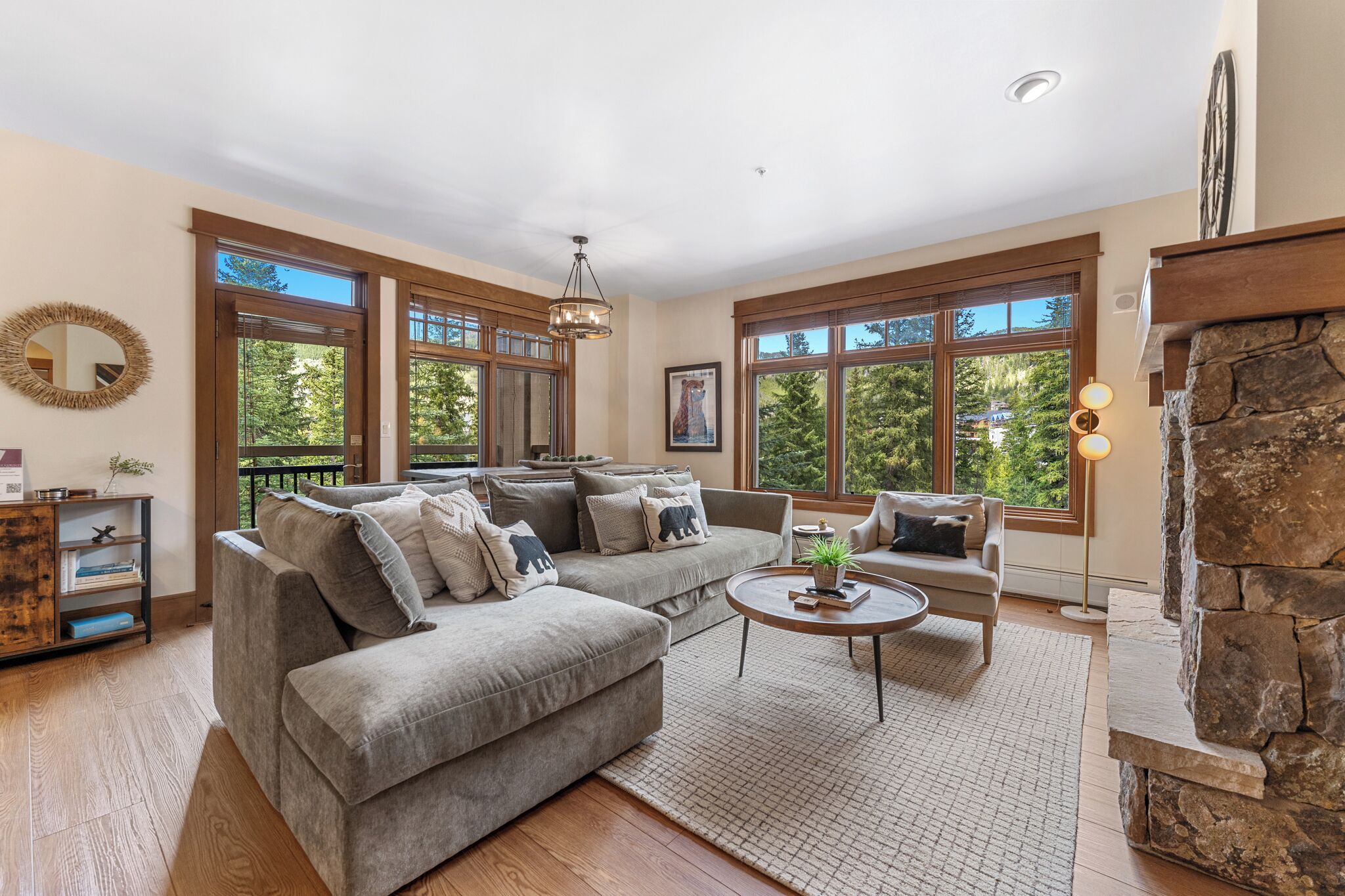 A spacious living room with a large sectional sofa, a round coffee table, and a stone fireplace.