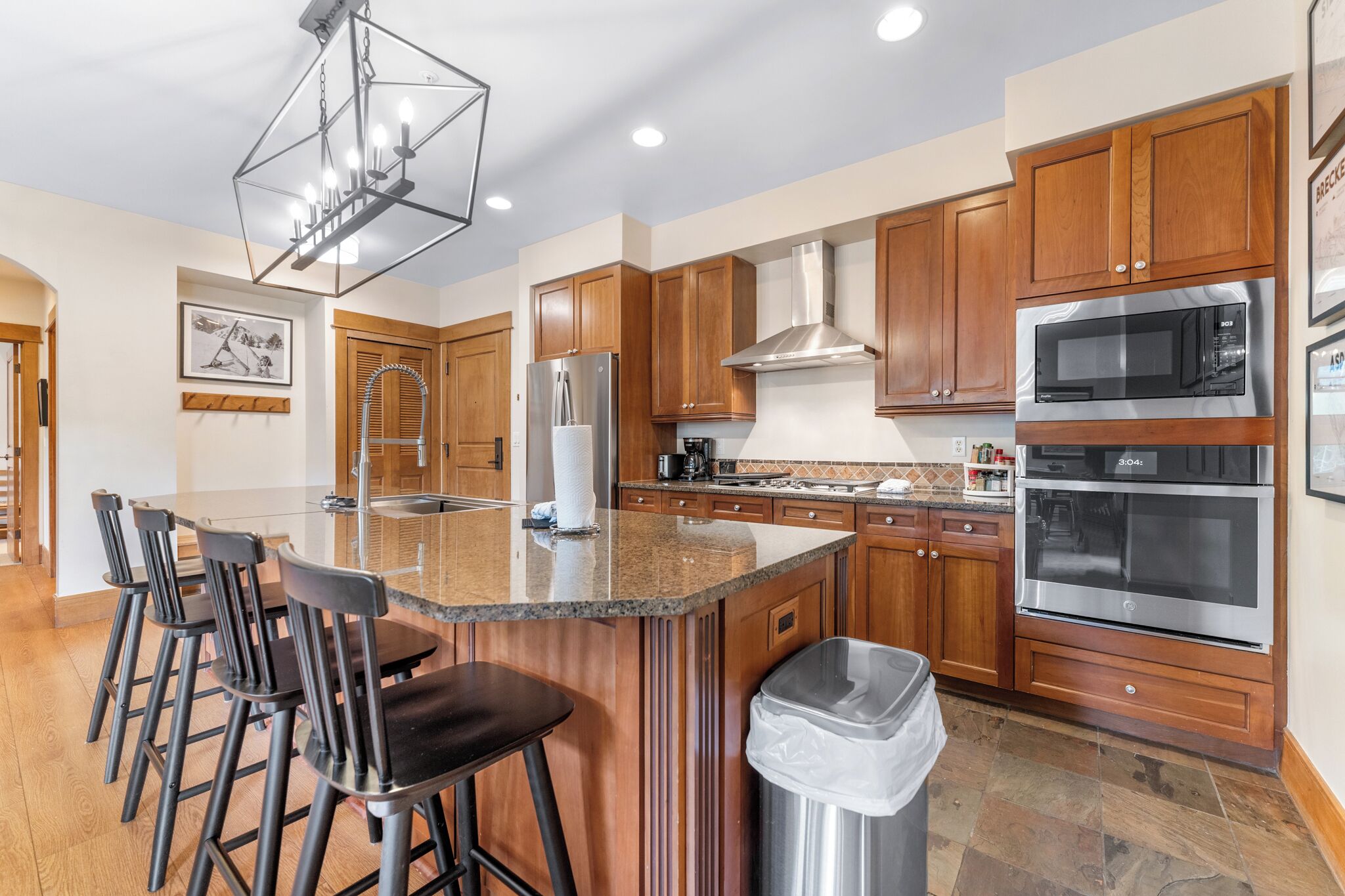 Una cocina moderna con armarios de madera, electrodomésticos de acero inoxidable y una isla central con taburetes de bar.