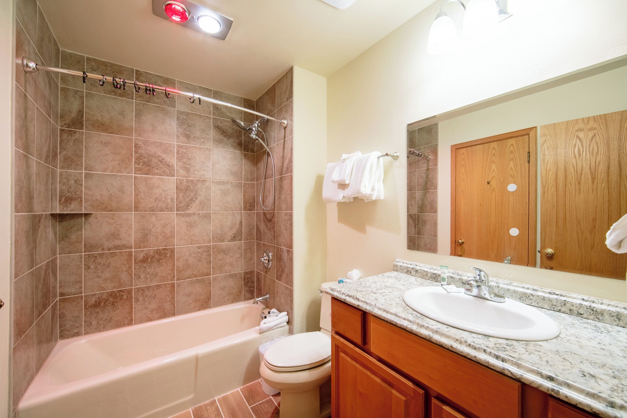 A bathroom with a bathtub, toilet, sink, and wooden vanity.