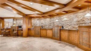 A spacious kitchen with wooden cabinets, stone walls, and pendant lighting.