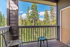 A wooden deck with a metal railing, a chair, and a small table.