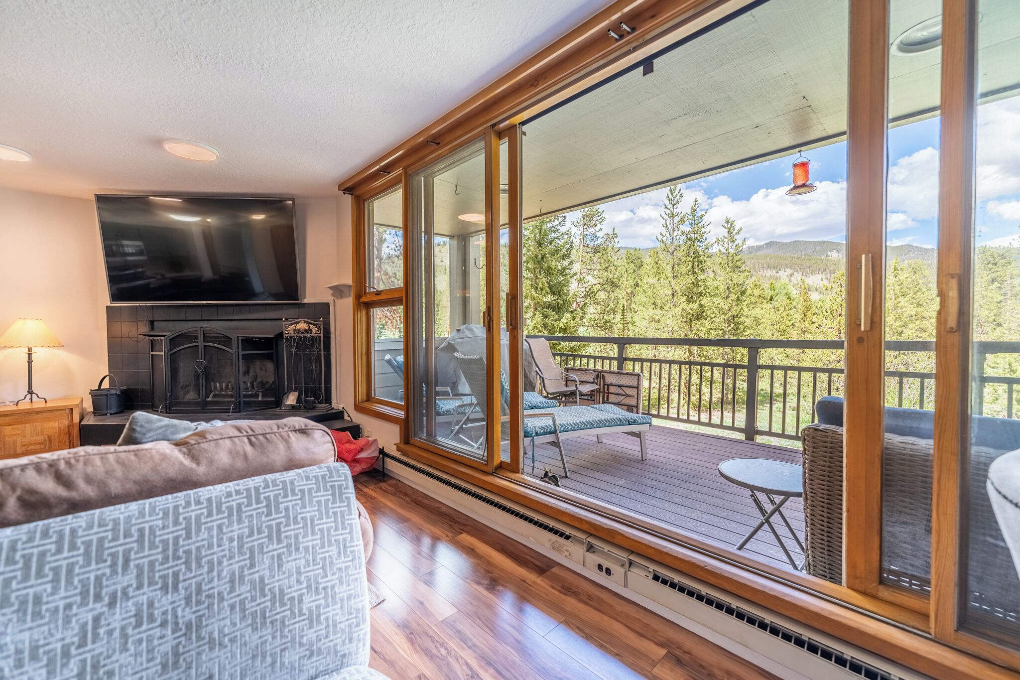A cozy living room with a fireplace, a large TV, and a balcony with outdoor furniture.