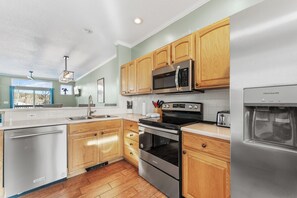 A modern kitchen with wooden cabinets, stainless steel appliances, and a dishwasher. - Srt253-3 (Silverthorne)