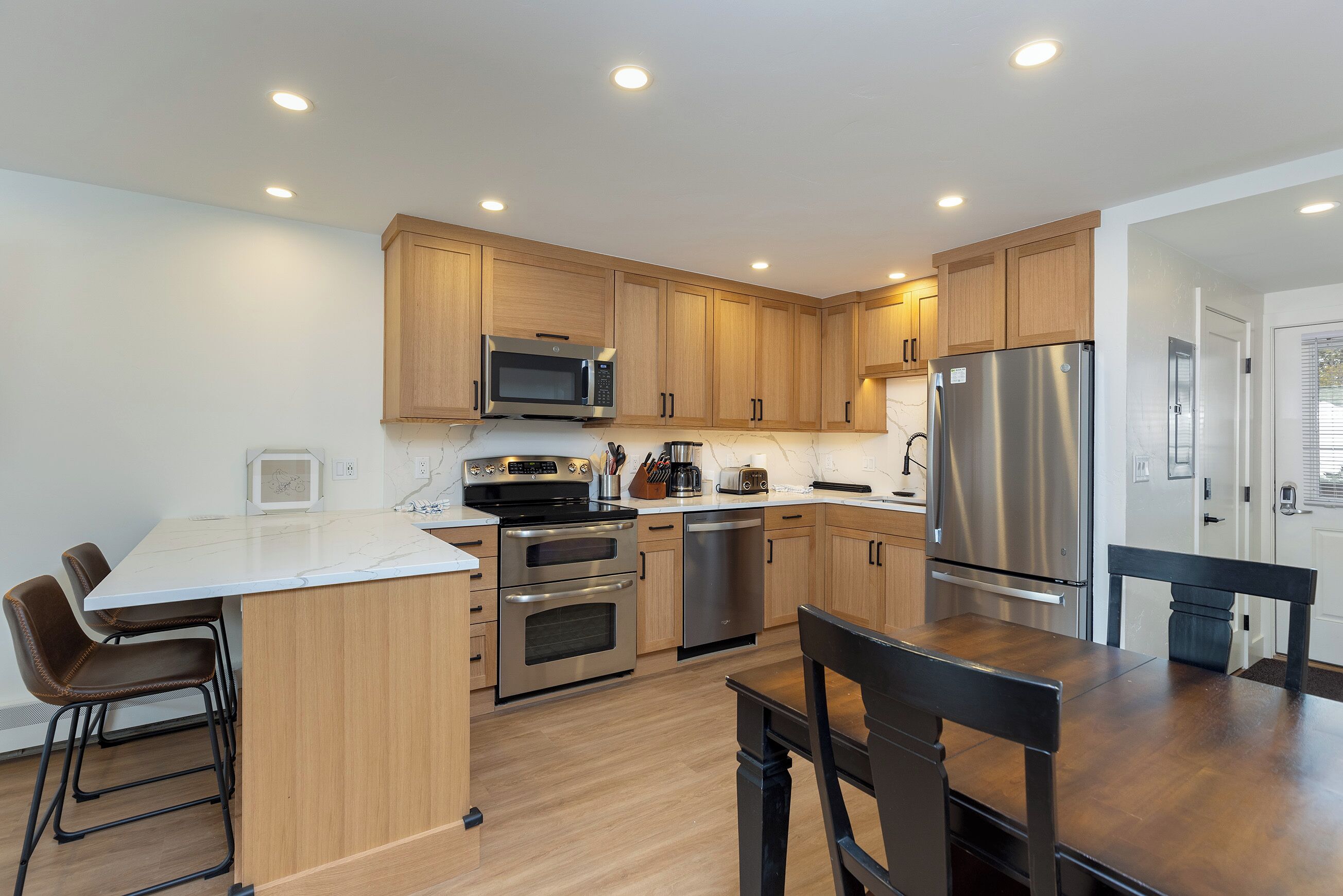 A modern kitchen with wooden cabinets, stainless steel appliances, and a central island with bar stools.