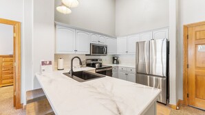 A modern kitchen with white cabinetry, stainless steel appliances, and a marble countertop. - Hr5982-2 (Keystone)
