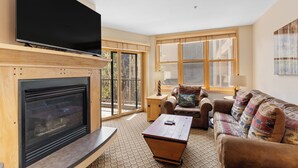 Ein Wohnzimmer mit Kamin, Flachbildfernseher, Sofa und Couchtisch.