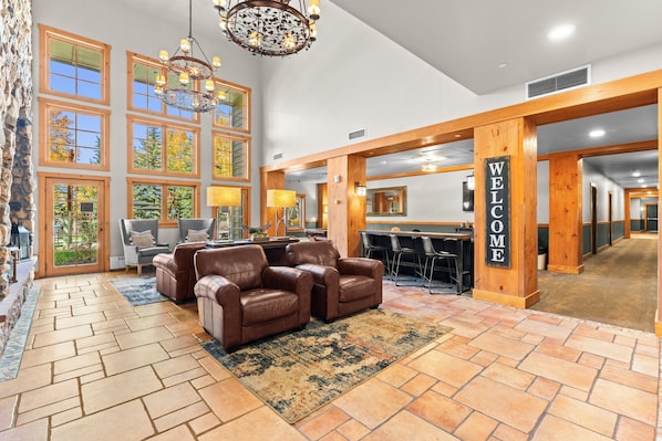 A lobby with a reception desk, leather sofas, a chandelier, and large windows.